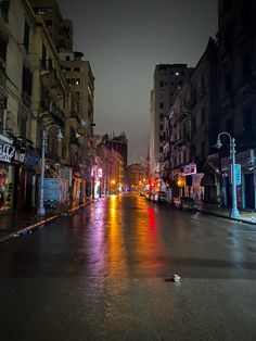 an empty city street at night with buildings on both sides