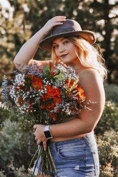 a woman wearing a hat holding flowers in her hands