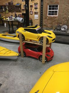 a yellow sports car sitting on top of a wooden stand next to two kayaks