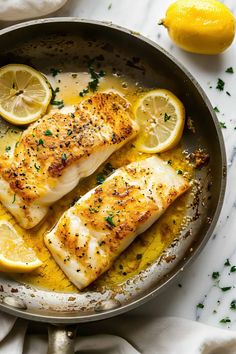 two fish fillets in a skillet with lemons and parsley