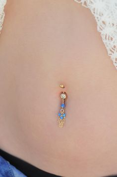 "A Hamsa belly button ring made with dangling blue Opal stones. This navel piercing is handmade of a 14k Goldfilled barbell, Hamsa hand pendant, and blue Opal stones. The Hamsa (or Hand of Fatima) is a middle-eastern symbol of good luck, said to keep evil spirits away. Do not hesitate to contact me for special requests and customization! ♥♥ ▶ 14K Goldfilled curved barbell, 11 mm long for a universal fit. ▶ Delicate 14K Goldfilled chain ▶ Blue Opal stones. ▶ 14K Goldfilled Hamsa pendant. ▶ Dangli Jewelry For Summer, Piercing Navel, Hand Pendant, Hamsa Pendant, Navel Ring, Navel Piercing, Belly Button Piercing, Navel Rings, Button Ring