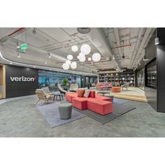 an office lobby with couches, chairs and tables in front of a verizon sign