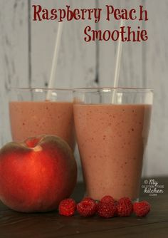 two glasses filled with raspberry peach smoothie on top of a wooden table