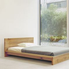 a bed that is made up in front of a window with trees outside the window