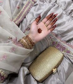 a woman's hand with henna and bracelets on top of her dress