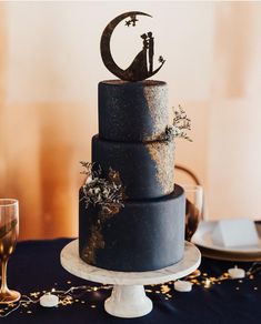 a wedding cake with a cat and moon decoration on the top, sitting on a table