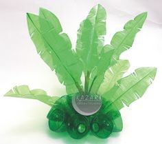 a green vase filled with leaves on top of a white table