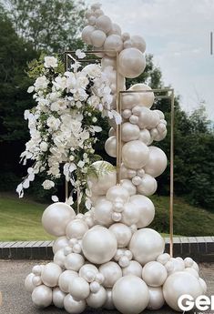 there is a tall tower made out of balloons and white flowers on the side of the road