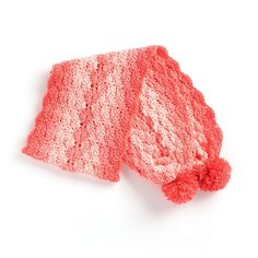 a pink crocheted hat with a red pom - pom