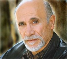 an older man wearing a black leather jacket and bow tie looking at the camera with a serious look on his face