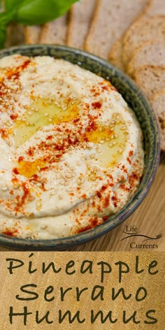 a bowl filled with hummus next to sliced bread