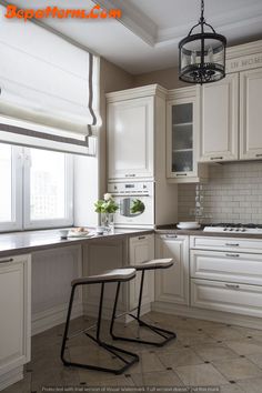 two stools sit in the middle of a kitchen with white cabinets and counter tops