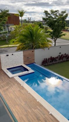 an above ground swimming pool surrounded by grass and palm trees in a backyard area with wooden decking