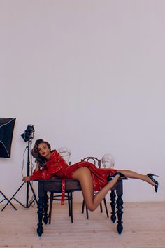 a woman in a red dress laying on a table