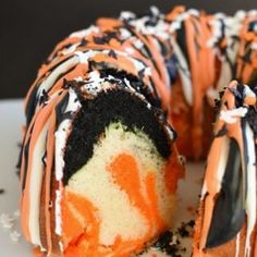 a cake that has been cut in half and is decorated with orange, black and white icing