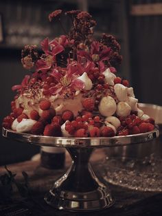 a cake on a silver platter topped with berries and marshmallows