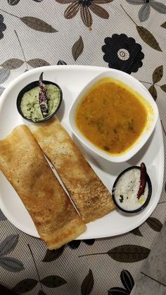 a white plate topped with two quesadillas and dipping sauces