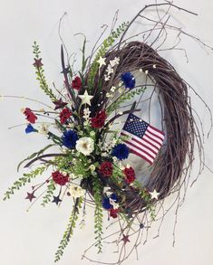 a wreath with an american flag and flowers in it on a white background, surrounded by branches