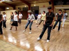 a group of people standing on top of a hard wood floor in a dance studio