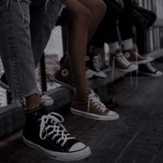 four people are sitting on a bench with their feet propped against each other's legs