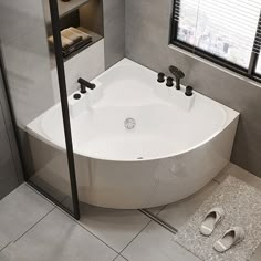 a large white bath tub sitting in a bathroom next to a pair of slippers