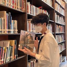 a person wearing a face mask and reading a book in a library with bookshelves