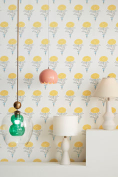 three lamps are hanging from the ceiling in front of a floral wallpaper