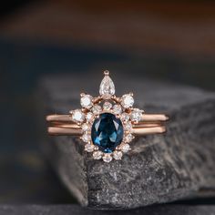 a blue and white diamond ring sitting on top of a rock