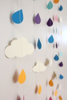 paper raindrops and clouds hanging from strings on a white wall in a child's room