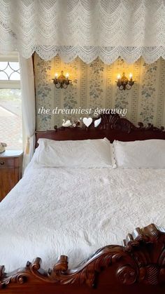 the bed is made with white linens and has an ornate headboard on it