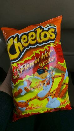 a person holding a bag of cheetos in their hand