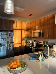 a bowl of oranges sits on the kitchen counter next to an oven and refrigerator