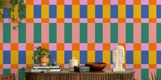 a room with colorful wallpaper and a table in front of it, surrounded by potted plants