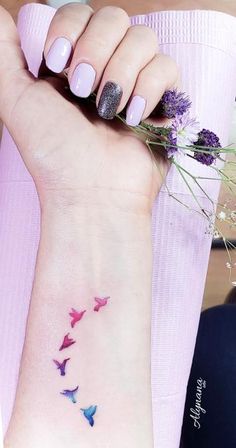 a woman's wrist with purple flowers and butterflies on her left hand, while she is wearing a pink dress