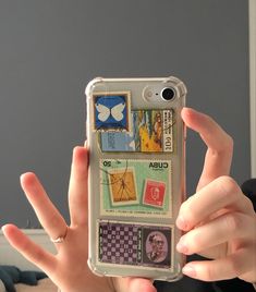 a person holding up a cell phone case with stamps on it