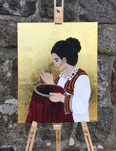 a painting of a woman holding her hands up in front of an easel with a gold background