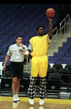 a man holding a basketball in his hand while standing next to another man on a court