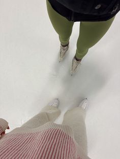 two people are standing on skis in the snow, looking down at their feet