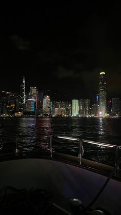 the city skyline is lit up at night as seen from a boat in the water