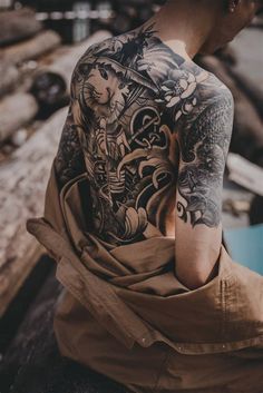 a tattooed man sitting on top of a wooden bench