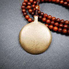 a wooden beaded necklace with a pendant on it