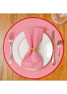 a place setting with red and white checkered napkins, silverware and wine glasses