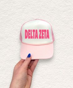 a pink and white hat with the word delta written on it