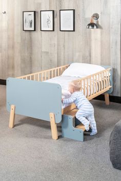 a toddler playing with a wooden bed frame