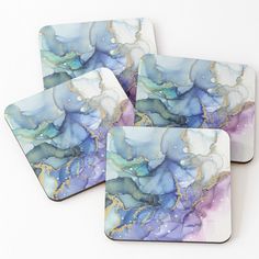 four coasters with blue, purple and gold designs on the top one has watercolor paint