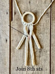 a crocheted doll hanging from a string on a wooden floor with the words join us