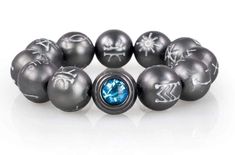 an assortment of black and silver beads with blue crystals in them on a white surface