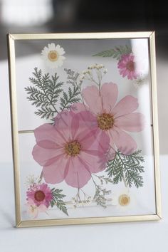 a glass frame with pink flowers and greenery