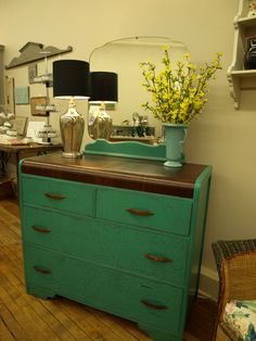 a green dresser sitting in front of a mirror on top of a hard wood floor