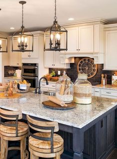 a large kitchen island with stools in front of it and lights hanging from the ceiling